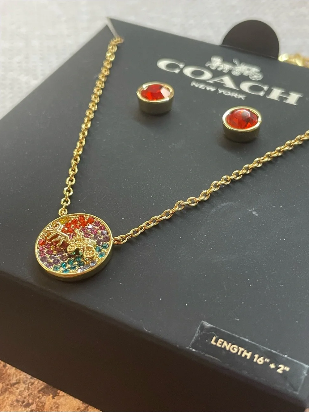 Coach 3-piece jewelry set featuring a gold-tone horse and carriage logo necklace